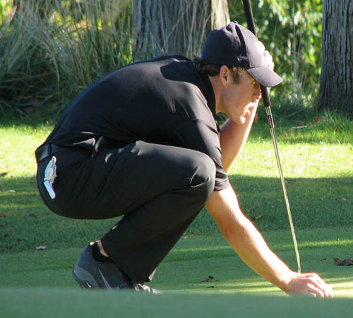Wildcat golfer lines up putt 
